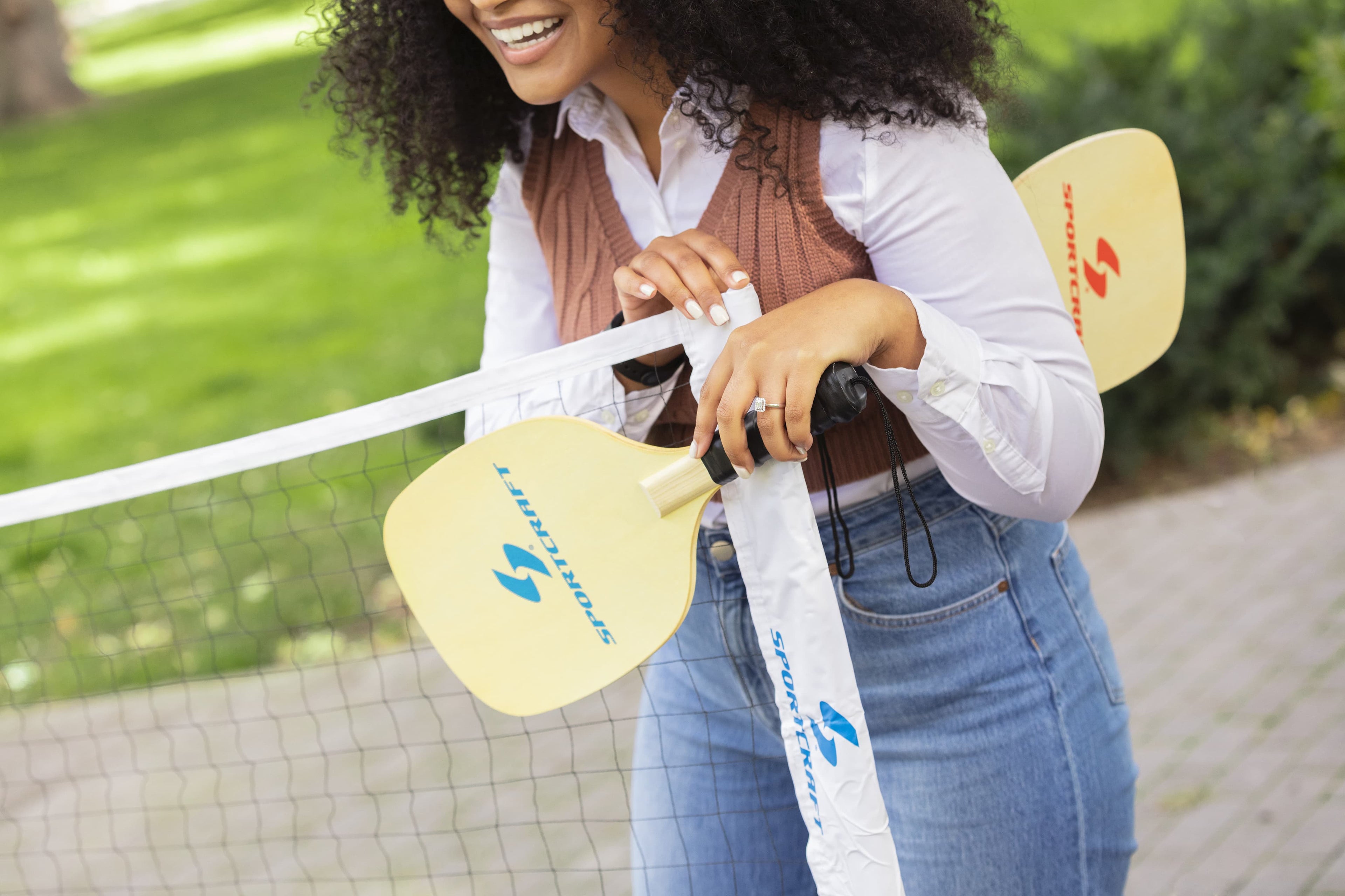 Sportcraft, Our products bring families and friends together. Women holding Pickleball paddles and standing next to a Pickleball net